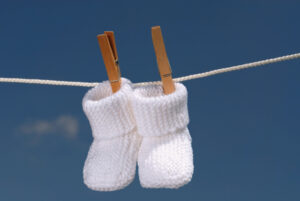 Chaussons blanc pour bébé accrochés avec des épingles sur un fil